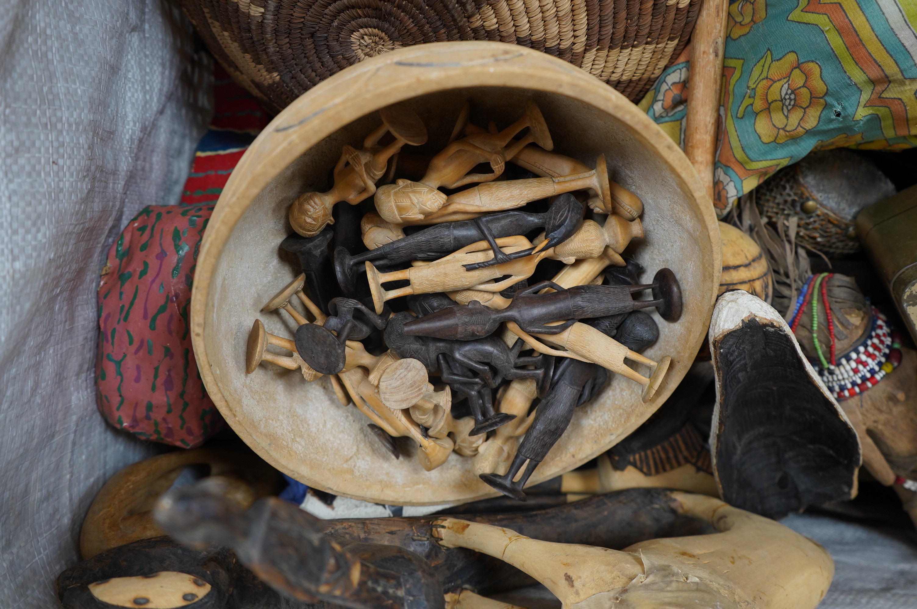 A quantity of African and Asian tribal carvings, basket woven dishes etc., largest dish 50cm diameter. Condition - poor to fair